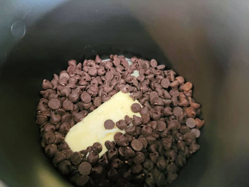 Chocolate chips and butter melting in a dark pan for no bake church window cookies