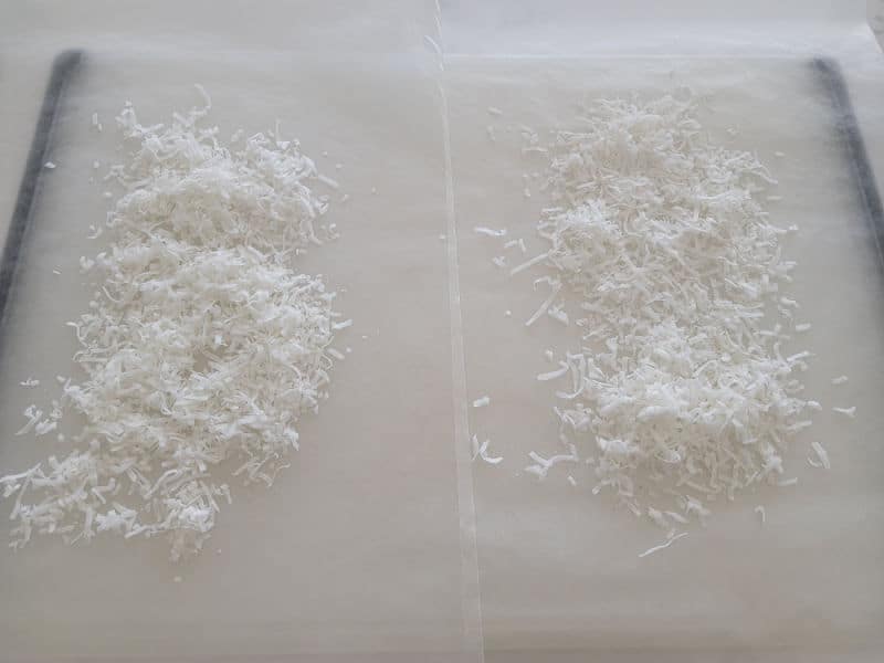 Shredded coconut spread in two lines on parchment paper for no bake church cookies