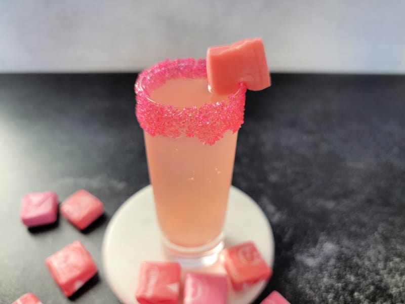 pink starburst shot garnished with a starburst candy on a white coaster