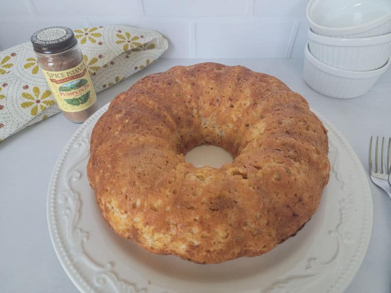 Pumpkin angel food cake on a white plate next to a jar of pumpkin pie spice, and a stack of bowls