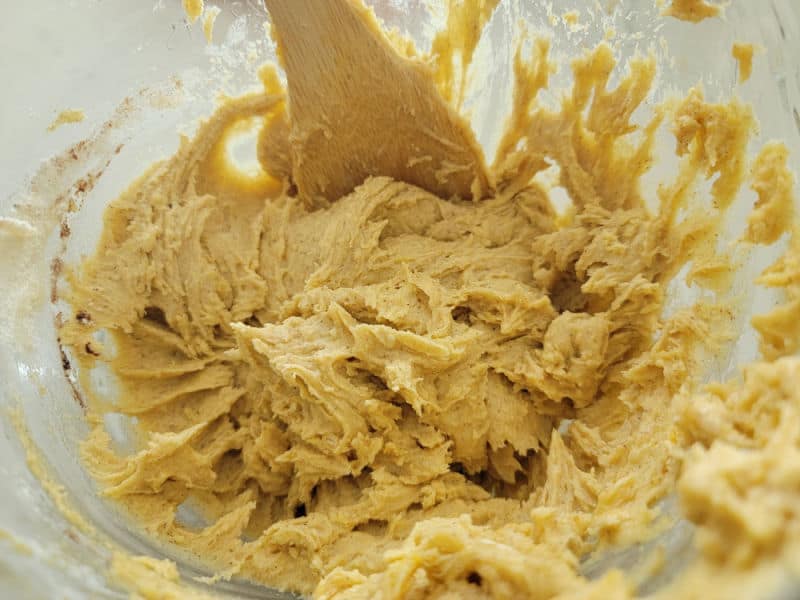 pumpkin snickerdoodle cookie dough in a glass bowl with a wooden spoon