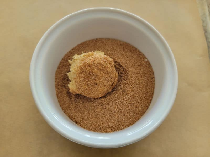 pumpkin snickerdoodle cookie dough ball in pumpkin pie spice in a white bowl