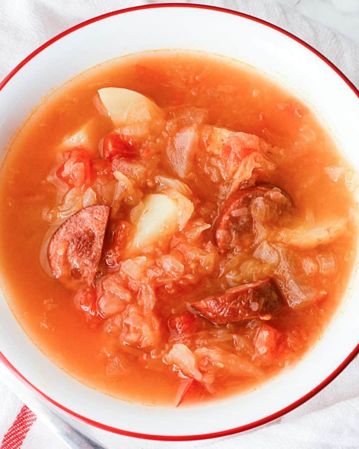 Sausage Sauerkraut Soup in a white bowl on a cloth napkin