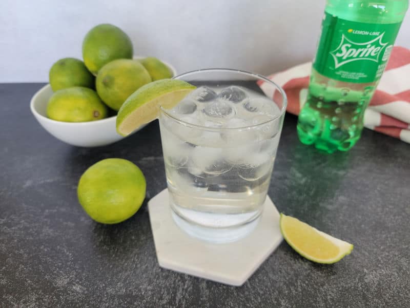 2 ingredient sprite and rum cocktail next to a bowl of limes and a bottle of Sprite