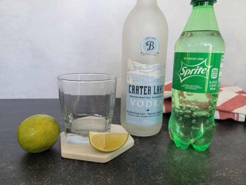 Lime, Cocktail glass on a coaster, bottle of Crater Lake Vodka, and a bottle of Sprite