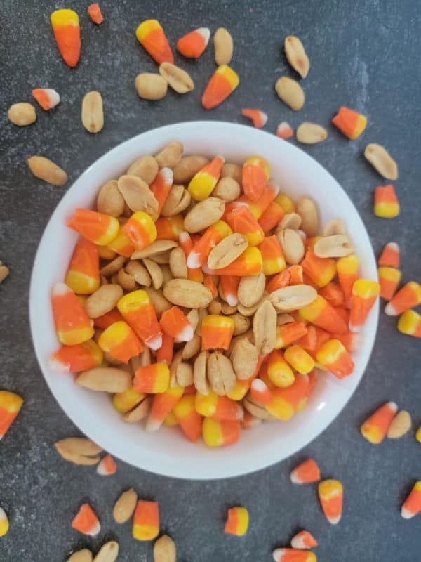 White bowl filled with candy corn and peanuts