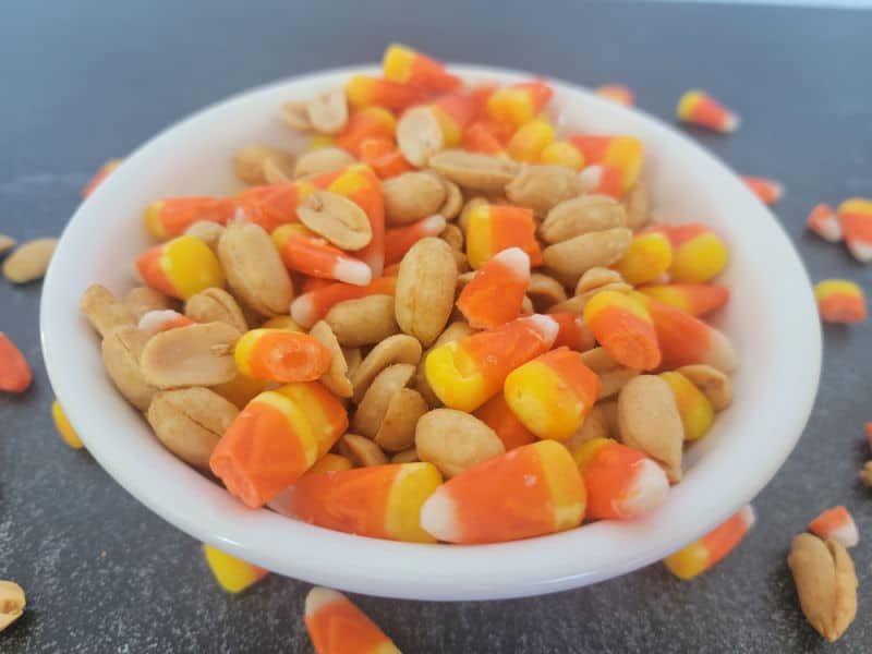 Candy corn and peanuts in a white bowl