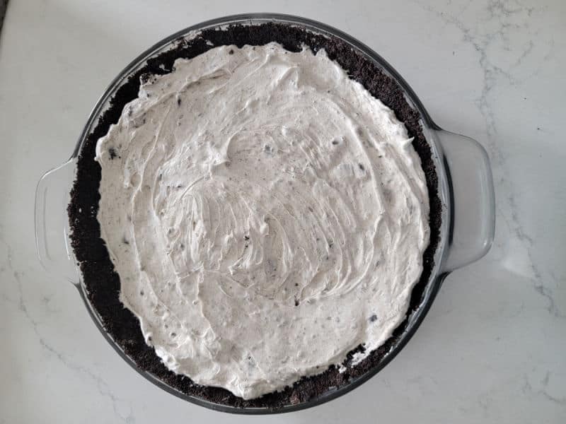 No Bake Oreo Cheesecake spread into a homemade Oreo crust in a glass pie dish