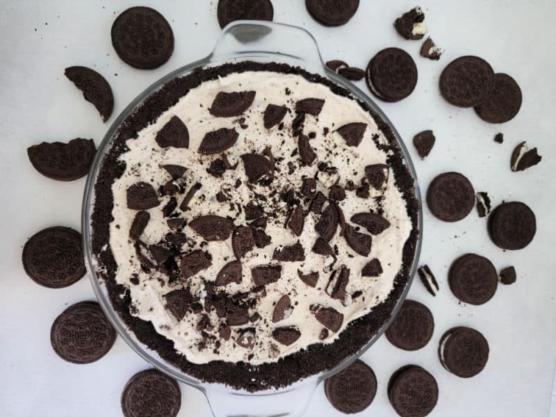 No Bake Oreo cheesecake covered in Oreo crumbs in a glass pie dish