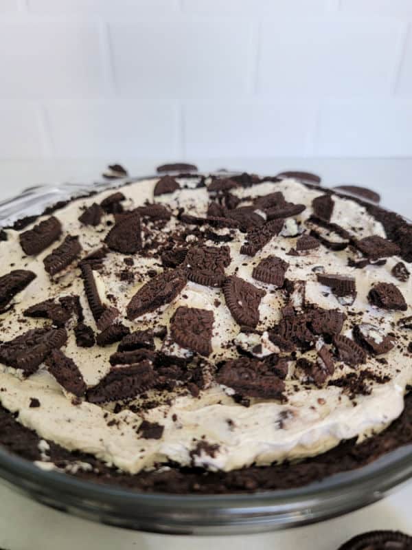 Oreo pieces on top of a No Bake Oreo Cheesecake with an Oreo crumb crust in a glass pie dish