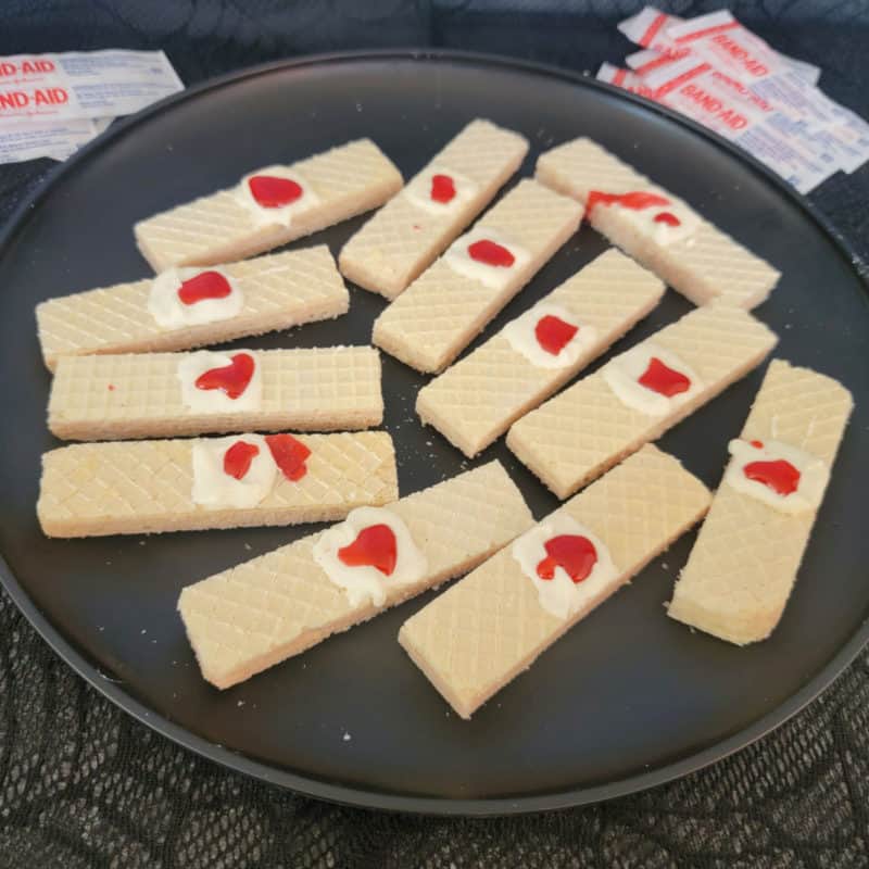 Bloody bandage cookies on vanilla wafers on a black plate