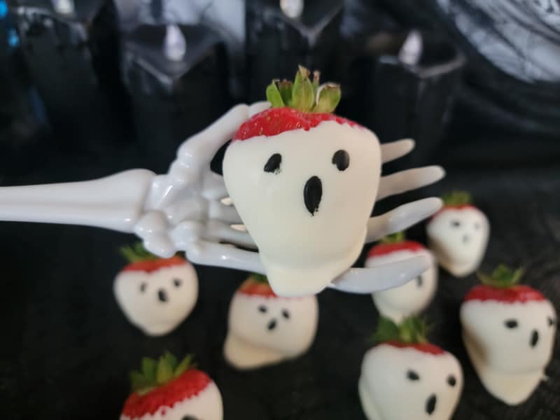 white chocolate ghost strawberry held on a skeleton hand