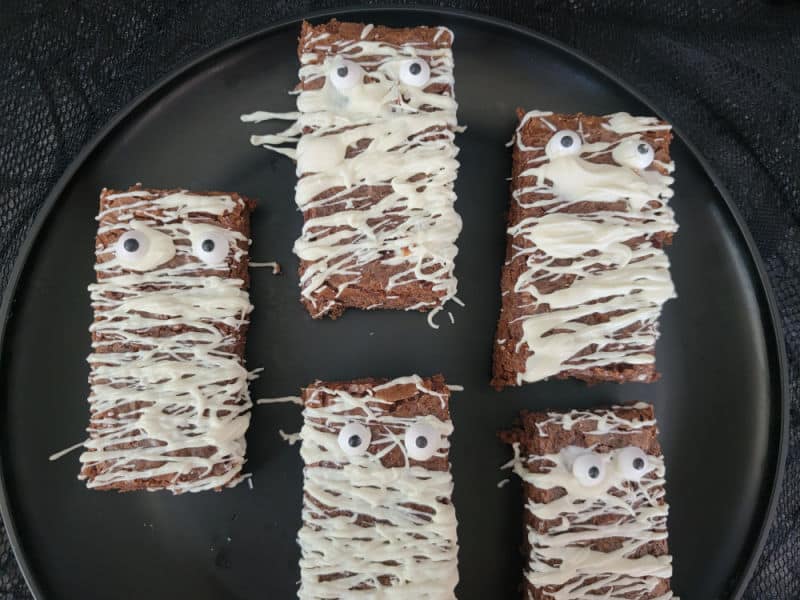 Mummy Brownies with candy eyes on a black circle plate