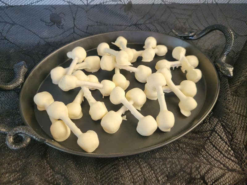 Almond bark pretzel bones on a black platter 