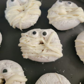 White chocolate mummy donuts on a black plate