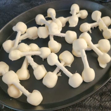 Halloween Pretzel Bones covered in white chocolate on a black platter