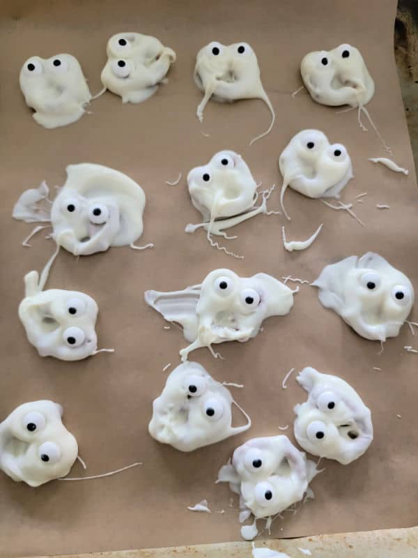 ghosts pretzels with candy eyes on parchment paper