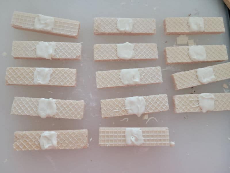 Vanilla wafers with white icing in the middle of them. 