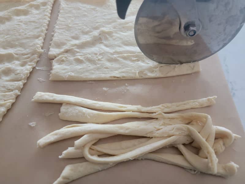 pizza cutter cutting strips of crescent rolls