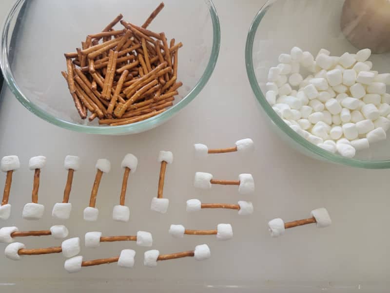 pretzel sticks and mini marshmallows in bowls next to pretzel bones