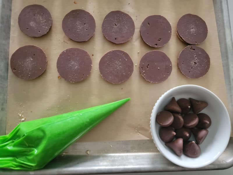 shortbread cookies on parchment paper with green icing and hershey kisses for witches hat