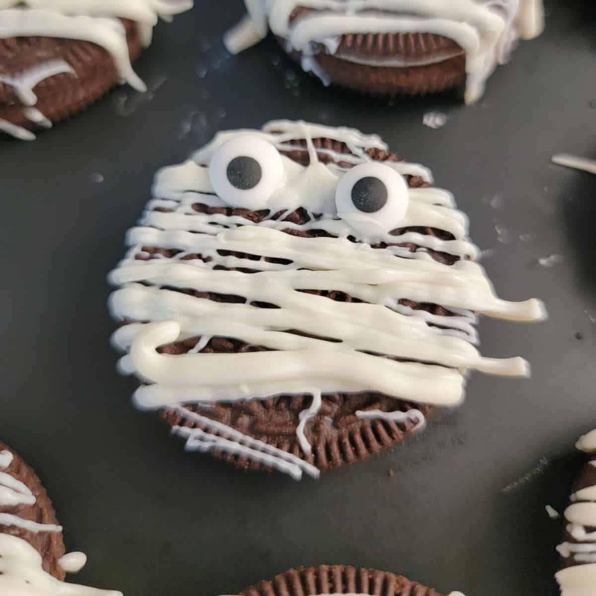 Mummy Oreo with candy eyes on a black plate