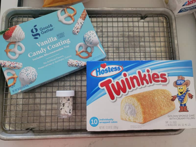 vanilla candy coating, candy eyes, and a box of twinkies on a baking pan
