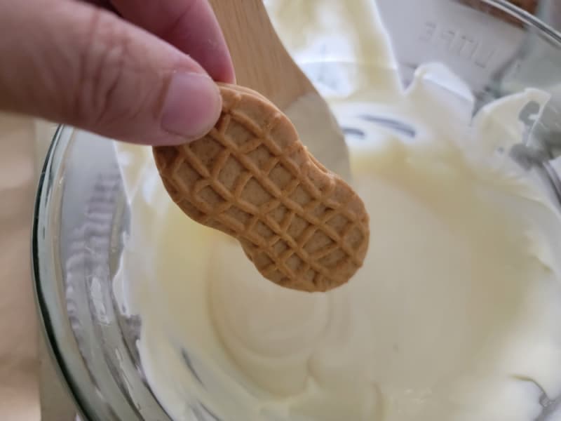 Nutter butter cookie dipping into melted white chocolate 