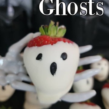 strawberry ghosts text over a white chocolate covered strawberry ghost on a skeleton hand