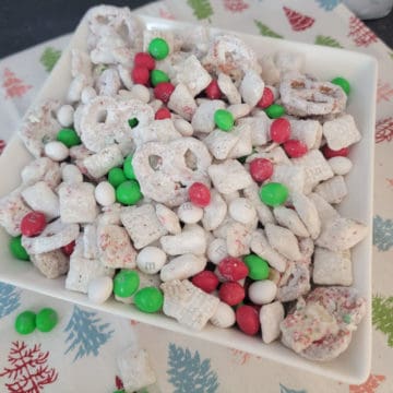 Christmas Reindeer Chow in a white bowl with a holiday cloth napkin