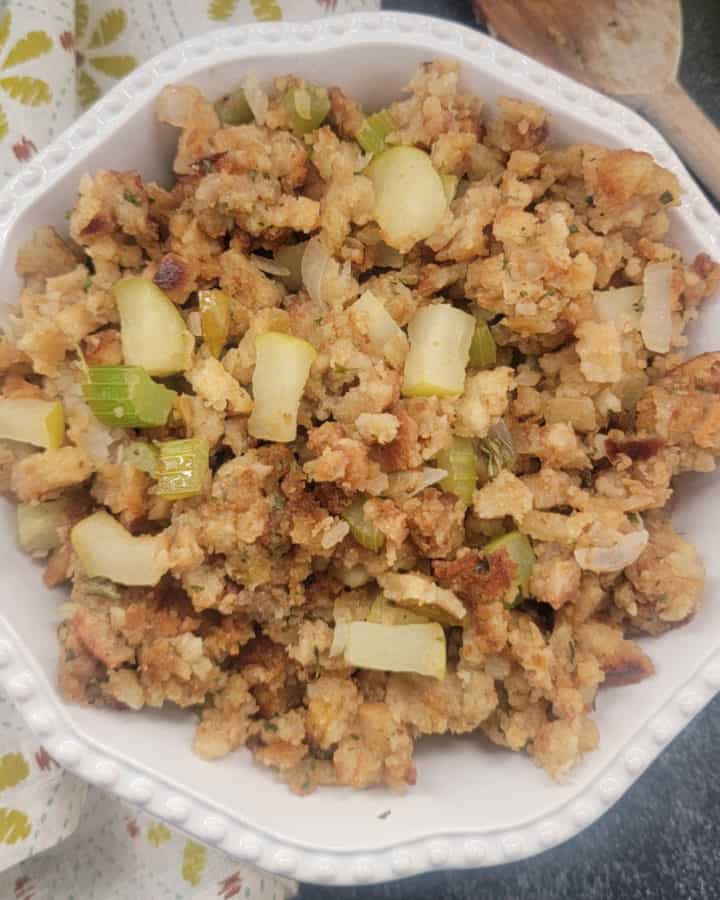 apple stuffing in a white bowl next to a cloth napkin and wooden spoon