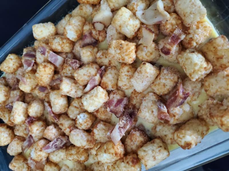 tater tots and bacon in a casserole dish for tater tot breakfast casserole