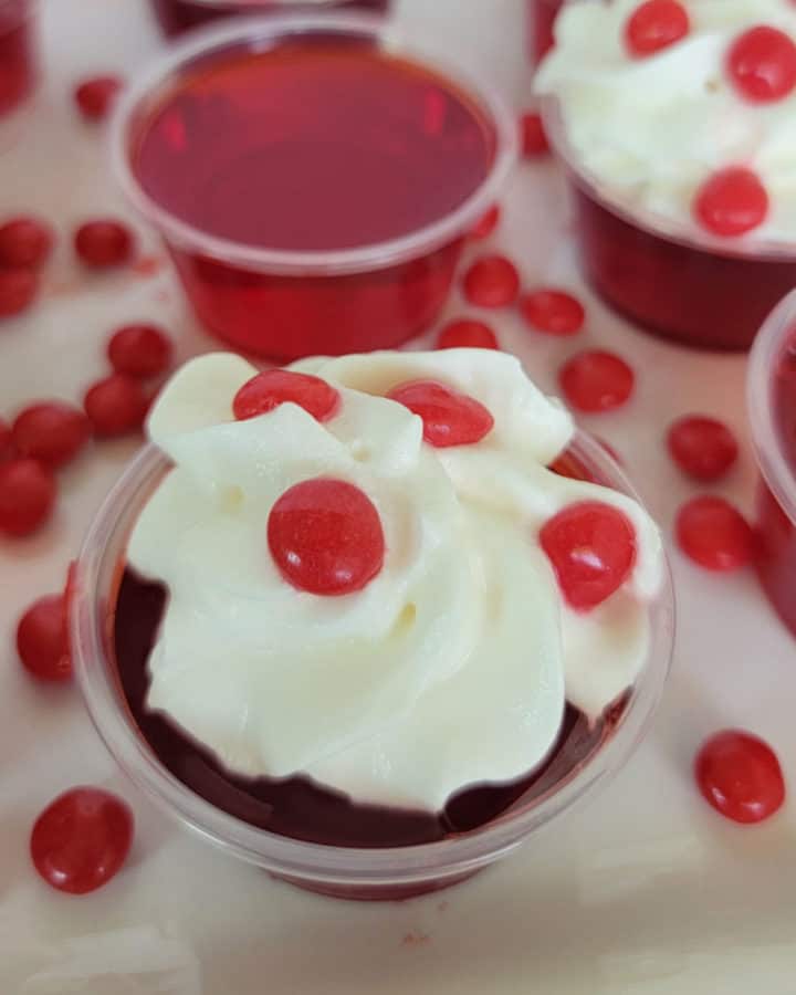 Fireball Jello Shot with whipped cream and a red hot candy on a white plate
