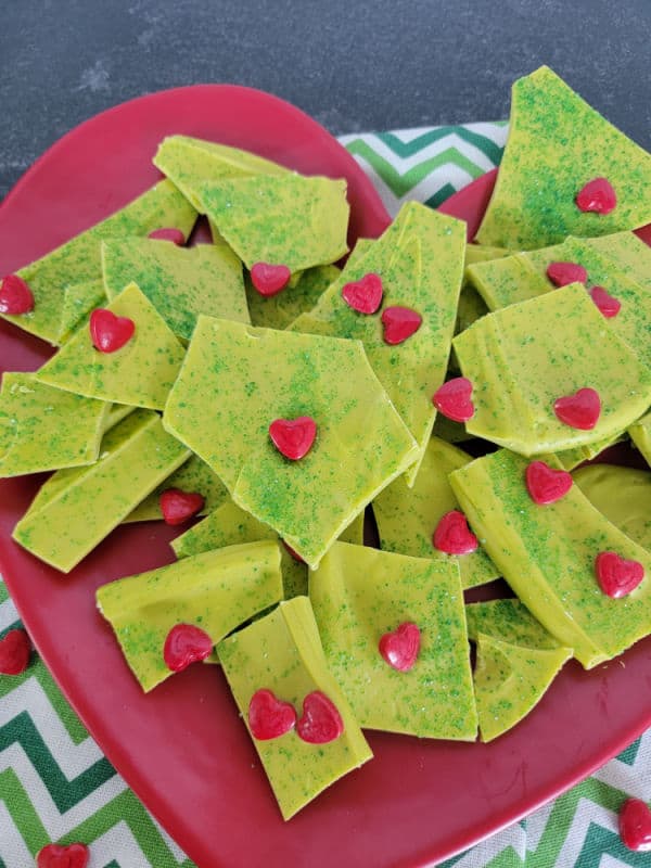 Vibrant green grinch bark with red hearts on a red heart plate with a green chevron patter towel under it. 