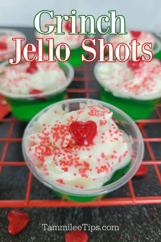 Grinch Jello Shots text written above multiple green Grinch Jello Shots with whipped cream, a red heart candy, and sprinkles