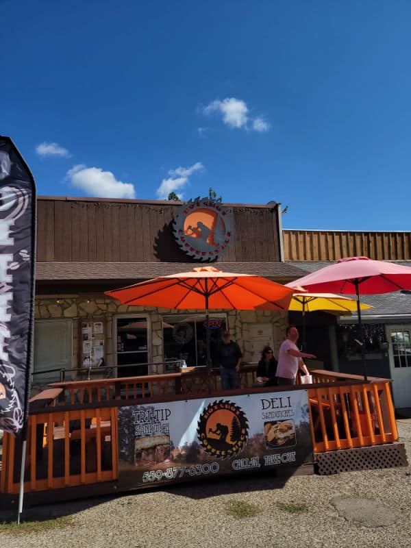 hot shot coffee exterior of the building with 3 umbrellas raised and a restaurant sign on the fence