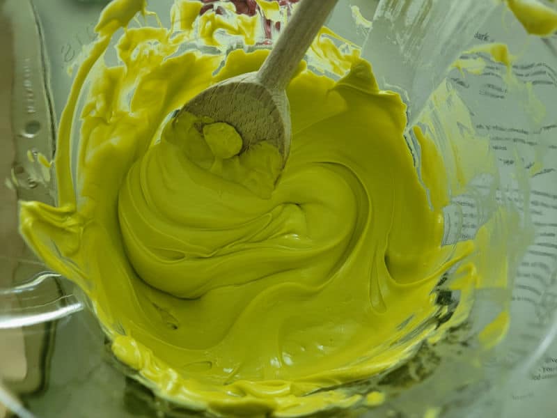 Green candy melt melted in a bowl with a wooden spoon.