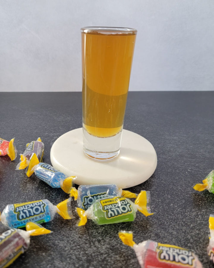 Jolly Ranch Shot on a white coaster surrounded by Jolly Rancher Candy