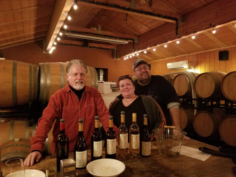 Tammilee Tips and Park Ranger John with Ray from Westbrook Wines with wine barrels in the background