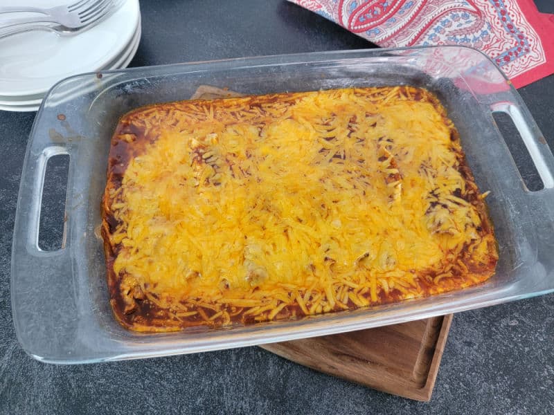 3 Ingredient Lazy enchiladas in a glass casserole dish on a wooden coaster