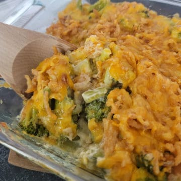 Wooden spoon scooping Broccoli Casserole from a glass baking dish