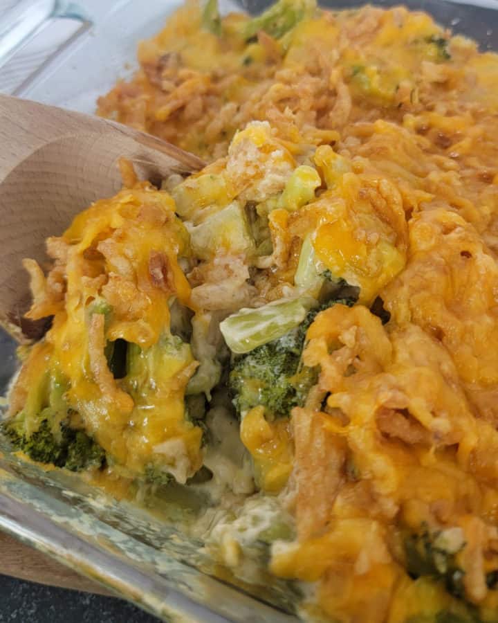 Wooden spoon scooping Broccoli Casserole from a glass baking dish