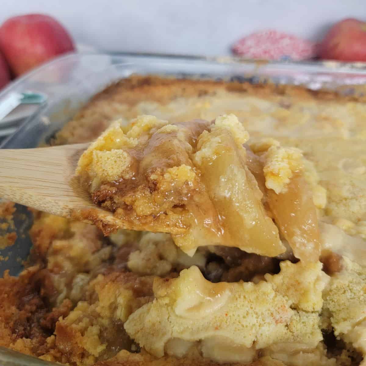 Wooden Spoon scooping Caramel Apple Dump Cake from a glass pan