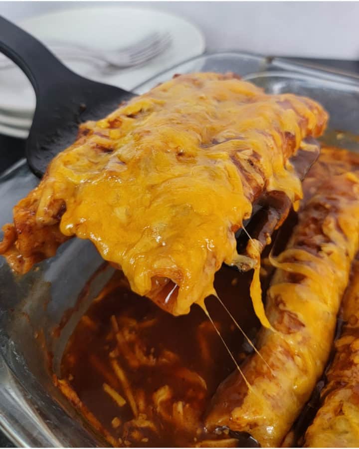 Spatula lifting lazy enchiladas out of a glass baking dish