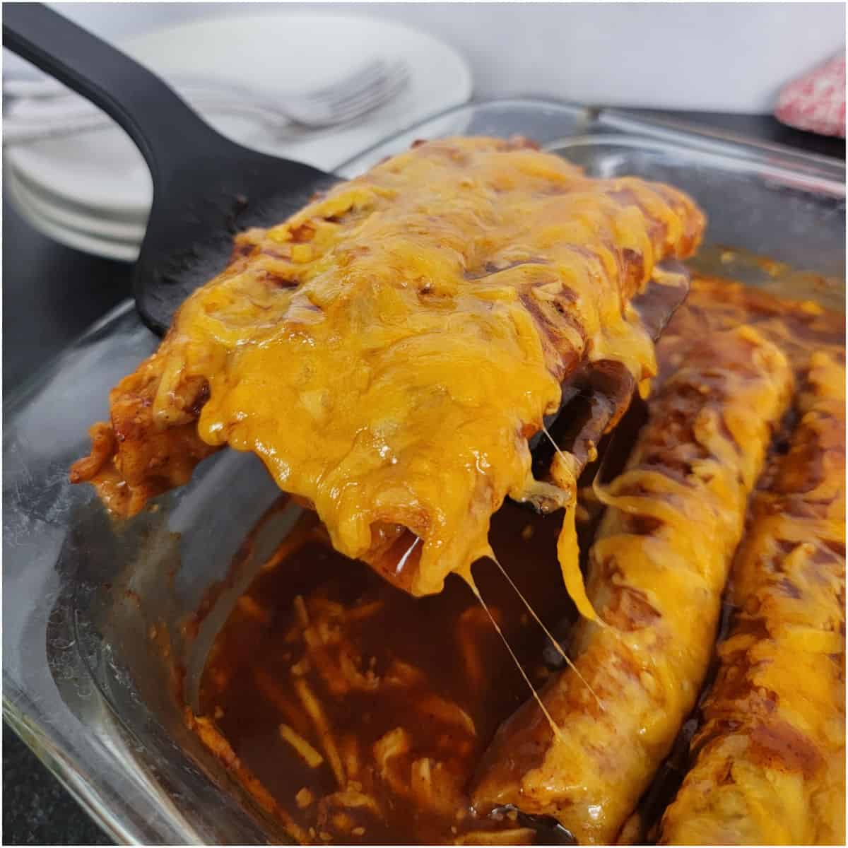 Spatula lifting lazy enchiladas out of a glass baking dish