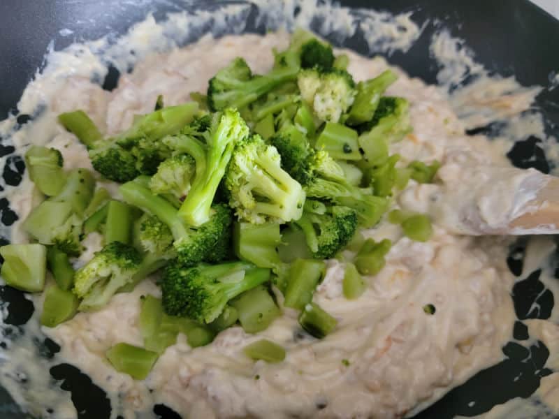Broccoli Florets mixing into a creamy mixture for Broccoli Casserole