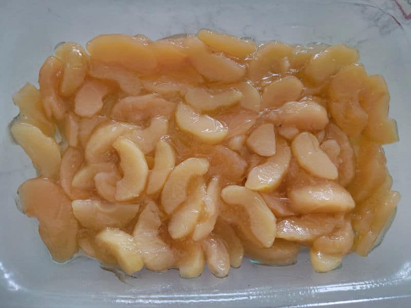 Apple pie filling spread in a glass casserole dish to make caramel apple dump cake