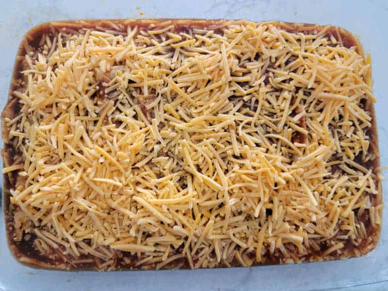 Shredded cheese spread over taquito enchiladas