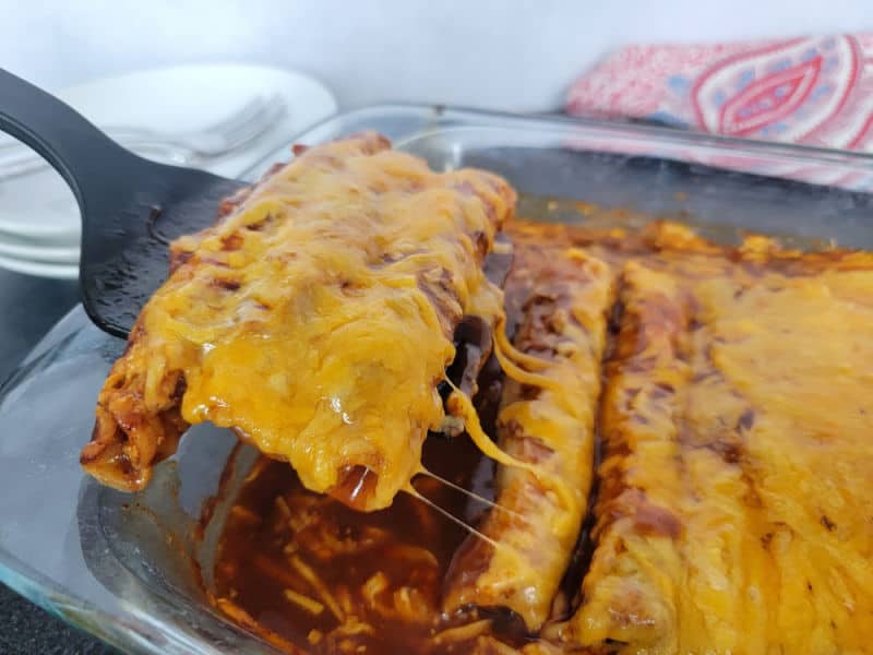 Cheezy lazy enchiladas scooping out of a glass casserole pan