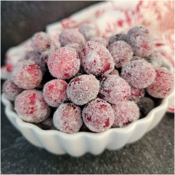 Sugared Cranberries in a white bowl with a red and white towel